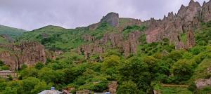 a large rocky mountain with trees and houses on it at Kirch Hotel & Restaurant in Goris