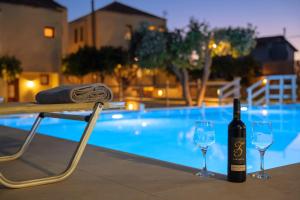 uma garrafa de vinho e dois copos ao lado de uma piscina em Villa Amarantos - Private pool em Stamnoí