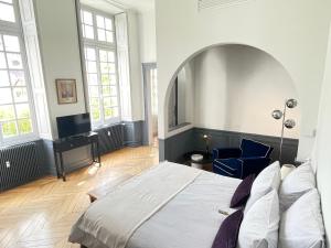 a bedroom with a large bed and a blue chair at Hôtel Particulier, Maison Jazey. in Semur-en-Auxois