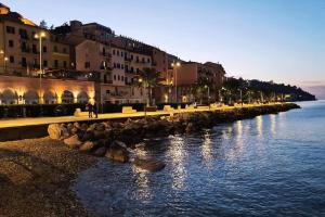 a city street with buildings and the water at night at Lo Scorcio sul porto in Porto Santo Stefano