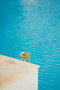 a drink in a glass sitting next to a pool at Mr and Mrs White Paros in Naousa
