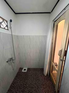 a bathroom with a shower with a door and a mirror at Toraja Sanggalangi Homestay in Rantepao +26 photos