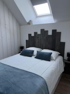 ein Schlafzimmer mit einem großen weißen Bett mit blauen Kissen in der Unterkunft Gîte à Saint-Marcan-Baie du Mont-Saint-Michel in Saint-Marcan