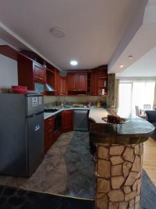 una gran cocina con armarios de madera y una isla de piedra. en Ivan Apartment Skopje, en Skopje