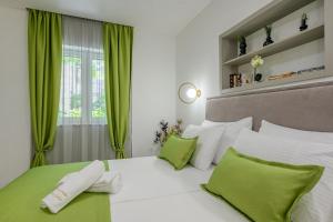 a bedroom with a bed with green and white pillows at Antique Spalato Luxury Rooms in Split