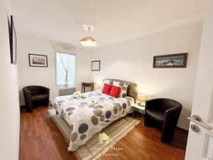 a bedroom with a bed and two chairs at Au gré des Vagues, vue mer, wifi, piscine chauffée in Concarneau