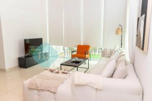 uma sala de estar com um sofá branco e uma cadeira laranja em Bloomfields - Private Townhouse At Reem Island em Abu Dhabi