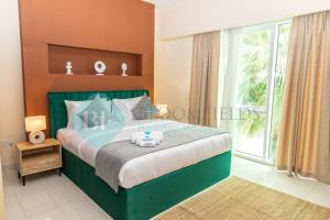 um quarto com uma cama verde e uma grande janela em Bloomfields - Private Townhouse At Reem Island em Abu Dhabi