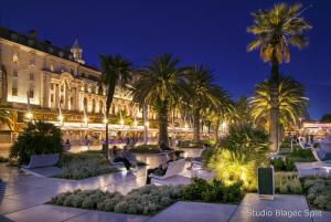 a courtyard with palm trees and a building at night at Antique Spalato Luxury Rooms in Split