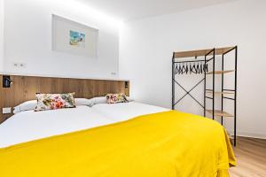 een slaapkamer met een groot bed en een gele deken bij Hostal Paris in Valladolid