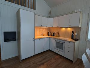 a kitchen with white cabinets and a tv in it at Lovely home by Glomma river! in Vidnes
