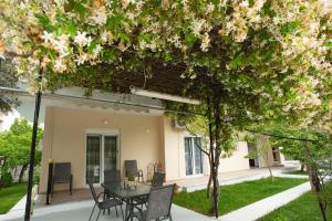 a patio with a table and chairs under a tree at LUCY APARTAMENT in Kamena Vourla