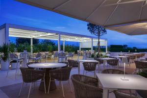 an outdoor patio with tables and chairs and umbrellas at Hotel Aurora in Lido di Jesolo