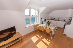 a dining room with a table with chairs and a television at Barton Road Apartment in Woolacombe