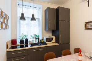 a kitchen with black cabinets and a microwave at Quiet rooms in the bustling city center in Budapest