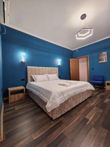 a bedroom with a large bed with a blue wall at Tirana Daily Rental Apartments 3 in Tirana
