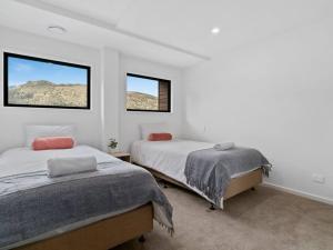 Habitación blanca con 2 camas y 2 ventanas en Contemporary & Plush - 3 Bedroom House Near Marina, en Queenstown