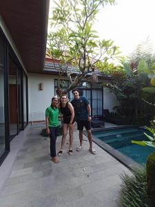 un groupe de trois personnes debout à côté d'une piscine dans l'établissement Sawitri Anandhita Luxury Villas, à Ubud