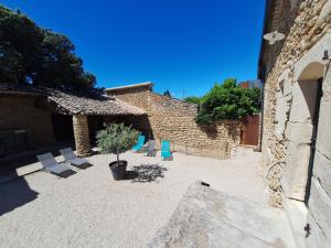 a courtyard with chairs and a tree and a building at Chez Véro Gîte & Chambres d'hôtes " Le Juvaquatre " in Suze-la-Rousse