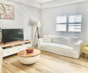 a living room with a white couch and a tv at Bondi Bliss ~ Stylish & Comfy Gem ~ Walk to Beach! in Sydney