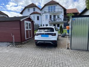 a white car parked in a driveway in front of a house at Ferienwohnung Lipps in Hammersbach +15 photos