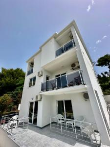 a white building with chairs and a balcony at Dilan’s apartments by the sea in Bar