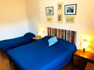 1 dormitorio con 2 camas azules y 2 lámparas en Giglio Bianco, en Campese