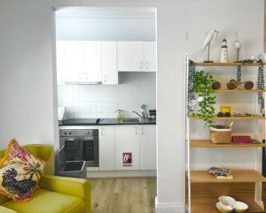a kitchen with white cabinets and a yellow couch at Bondi Bliss ~ Stylish & Comfy Gem ~ Walk to Beach! in Sydney