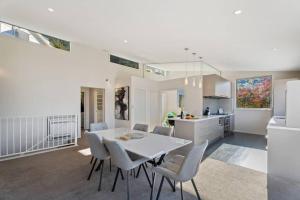 a kitchen and dining room with a white table and chairs at Luxury Retreat - Matakauri in Queenstown