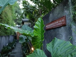 een bord aan de zijkant van een muur met planten bij Sawitri Anandhita Luxury Villas in Ubud