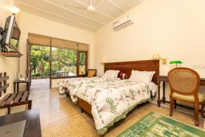 um quarto com uma cama, uma cadeira e uma janela em Lutyens Bungalow em Nova Deli