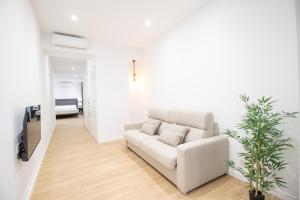 een witte woonkamer met een bank en een tv bij BedTime Suites by Concept Flats in Valencia