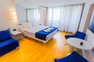 a bedroom with a bed and two blue chairs at Orbi City on the Beach in Batumi