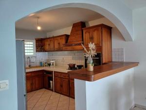 Una cocina con gabinetes de madera y encimera. en Villa Cannelle 2, en Étang-Salé