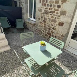 una mesa con sillas y un tazón de flores. en Gîte à Saint-Marcan-Baie du Mont-Saint-Michel en Saint-Marcan