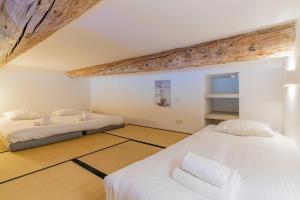 Cette chambre comprend 2 lits dans une chambre dotée de murs blancs et de plafonds en bois. dans l'établissement L'Arsenal - très bel appartement sur le Vieux-Port, à Marseille