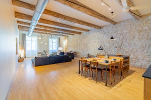 - un grand salon avec un mur en pierre, une table et des chaises dans l'établissement L'Arsenal - très bel appartement sur le Vieux-Port, à Marseille
