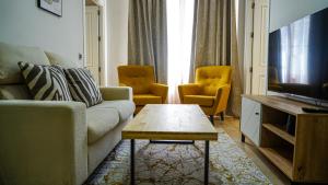 sala de estar con sofá y 2 sillas en Apartamentos Puente Romano Suites Parking Gratis, en Mérida