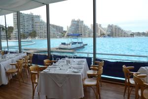 - un restaurant avec des tables et des chaises offrant une vue sur l'eau dans l'établissement Vive San Alfonso del Mar, à Algarrobo