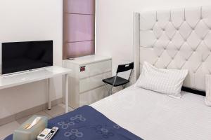 a bedroom with a bed and a tv and a chair at RedLiving Apartemen Eco Home - Wieg's Room Tower B Yashinoki in Tangerang