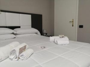 Una gran cama blanca con toallas encima. en Hotel Siros en Verona