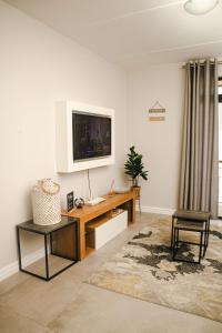 uma sala de estar com uma secretária e uma televisão na parede em Modern 2 Bedroom 2 Bathroom Apartment Incl Gym em Ballito