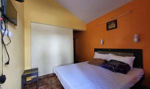 um quarto com uma cama com uma parede laranja em FabExpress MK Homes em Kodaikanal
