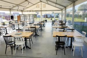 um restaurante vazio com mesas, cadeiras e janelas em Fantazja Resort Zator em Zator