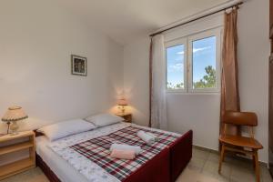 a bedroom with a bed and a window and a chair at Beachfront House Nada - Happy Rentals in Karlobag