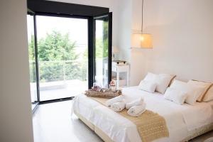 a bedroom with a large white bed with towels on it at Serenity Villa in Sani in Sani Beach