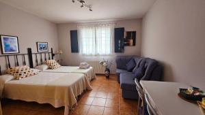 1 dormitorio con 2 camas y sofá azul en Apartamentos Castello, en Cartavio