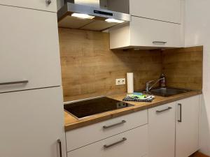 a kitchen with white cabinets and a sink at Gabi mit Pool und Sauna in Übersee