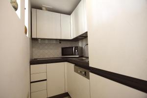 a small kitchen with white cabinets and a microwave at Testaccio View Holiday House in Rome