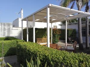 a white pergola with two wooden chairs under it at Casa Alba by My Home Apulia in Torre Lapillo